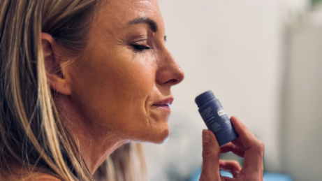 Žena so zatvorenými očami privoniava k tyčinke dōTERRA PastTense Stick Plus Sweet Gum